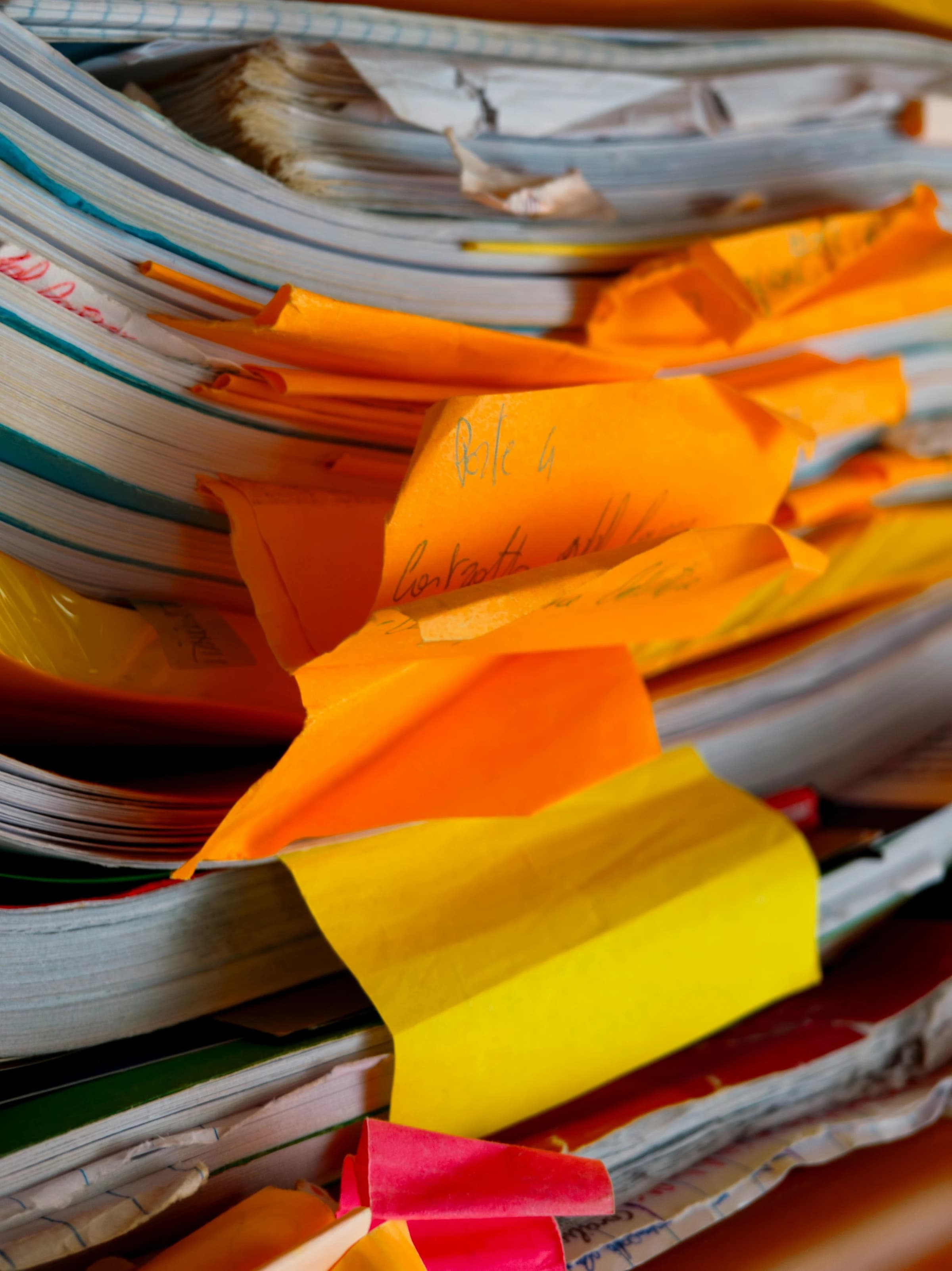 A close-up of a messy stack of orange papers and files